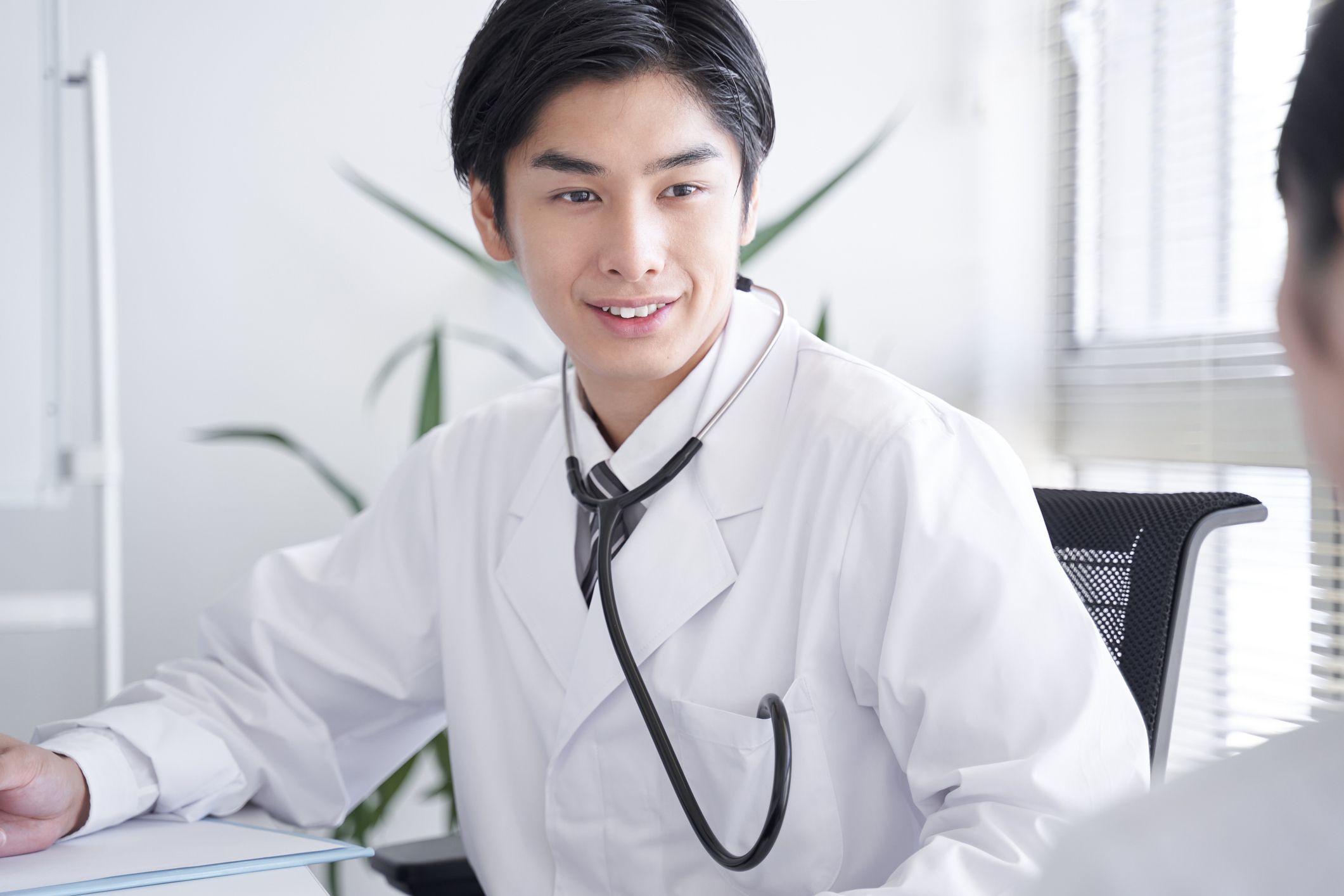 a japanese male doctor examining a female office worker
